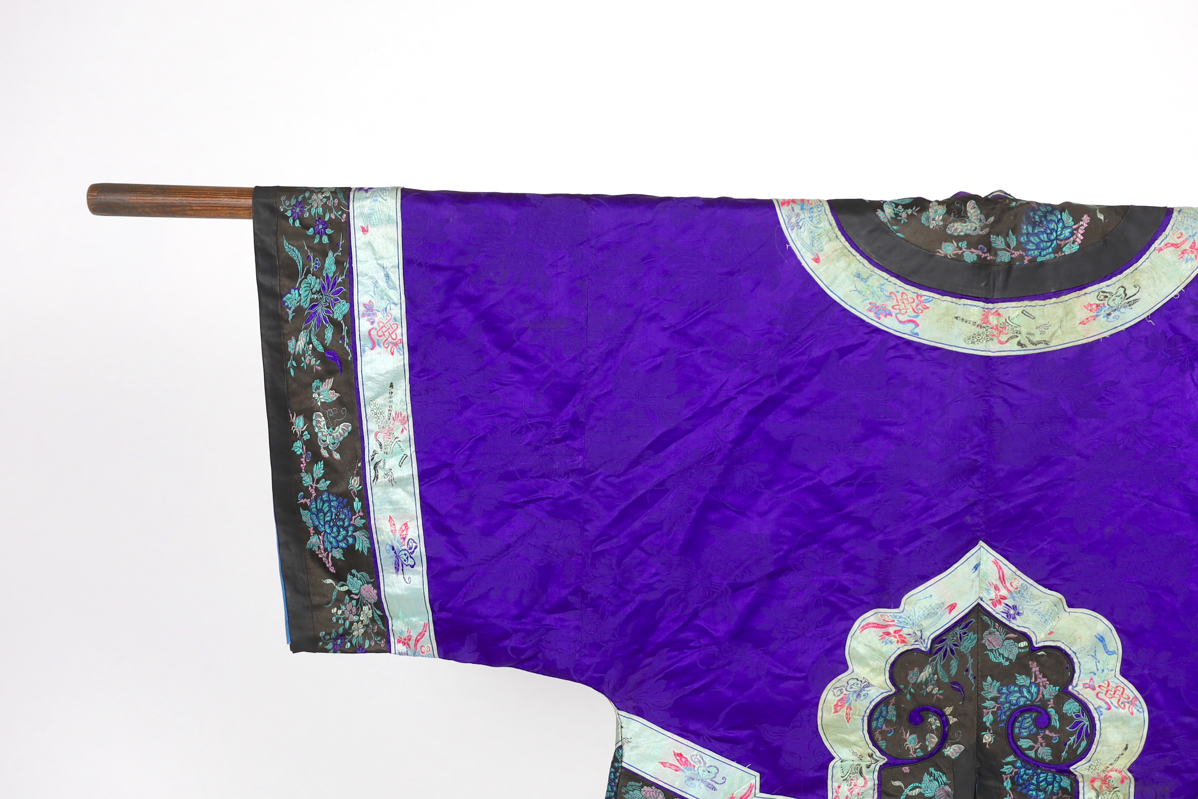 A Chinese purple damask jacket, circa late 19th / early 20th century, decorated with black and turquoise embroidered braiding with auspicious symbols, butterflies and flowers embroidery, 63cm long